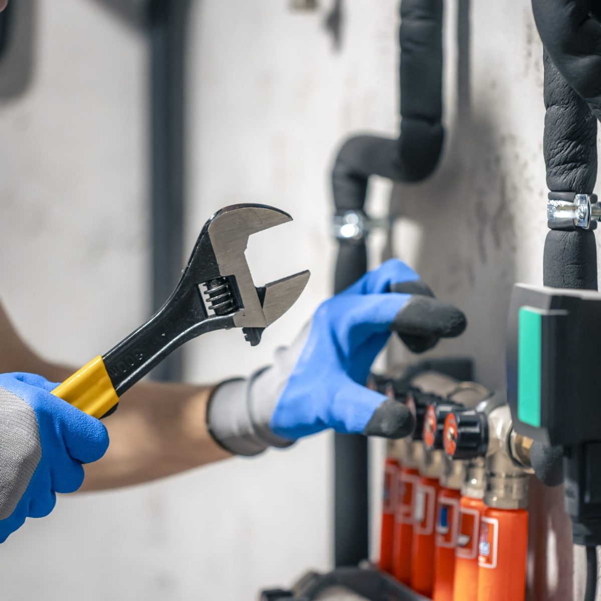 A man installs a heating system in a house and checks the pipes with a wrench. A man installs a heating system in a house and checks the pipes with a wrench. Adjusting heating valves in a residential building. A plumbing and heating technician works.